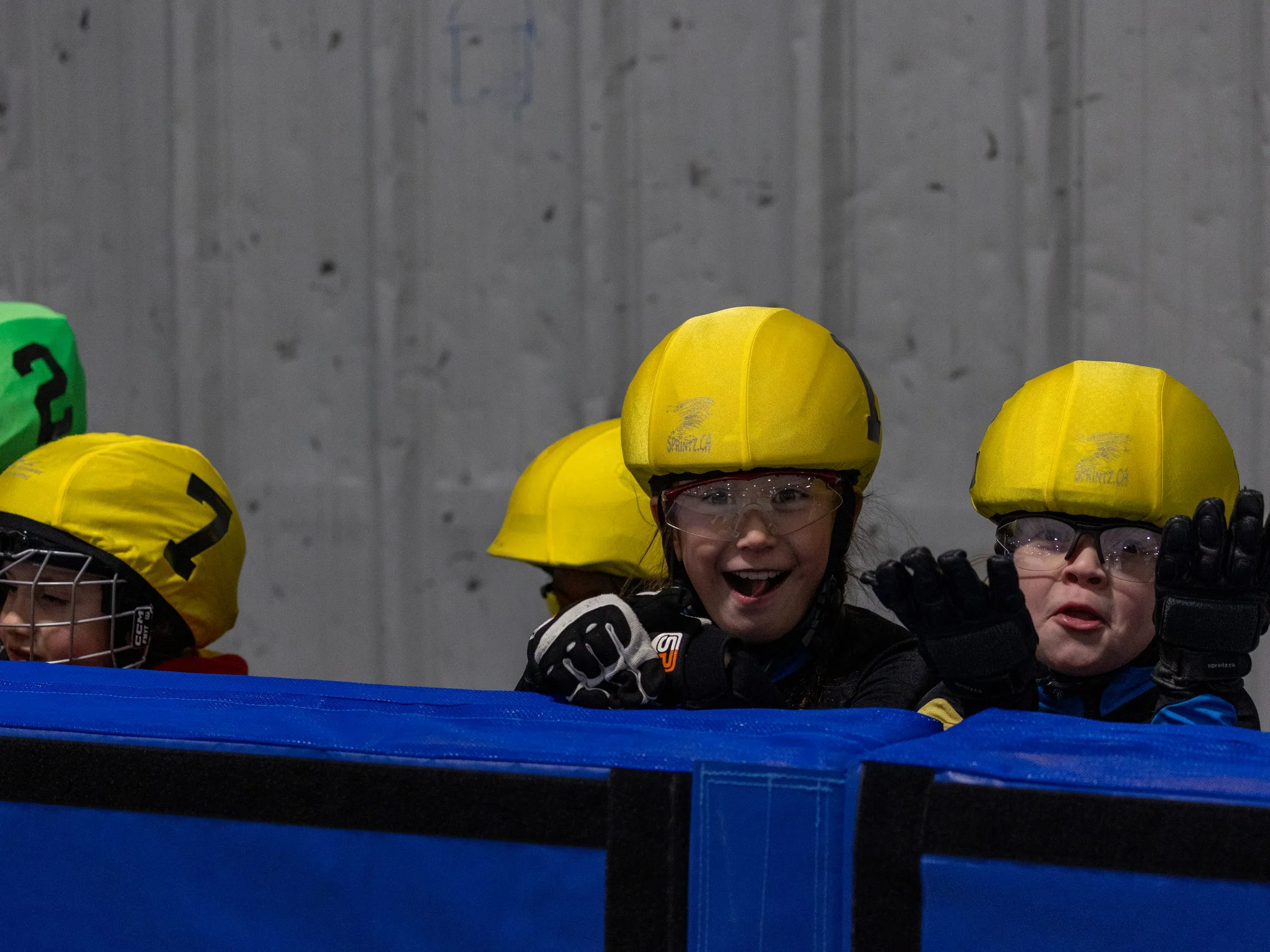 Young skaters cheering from the side of the rink at a club race