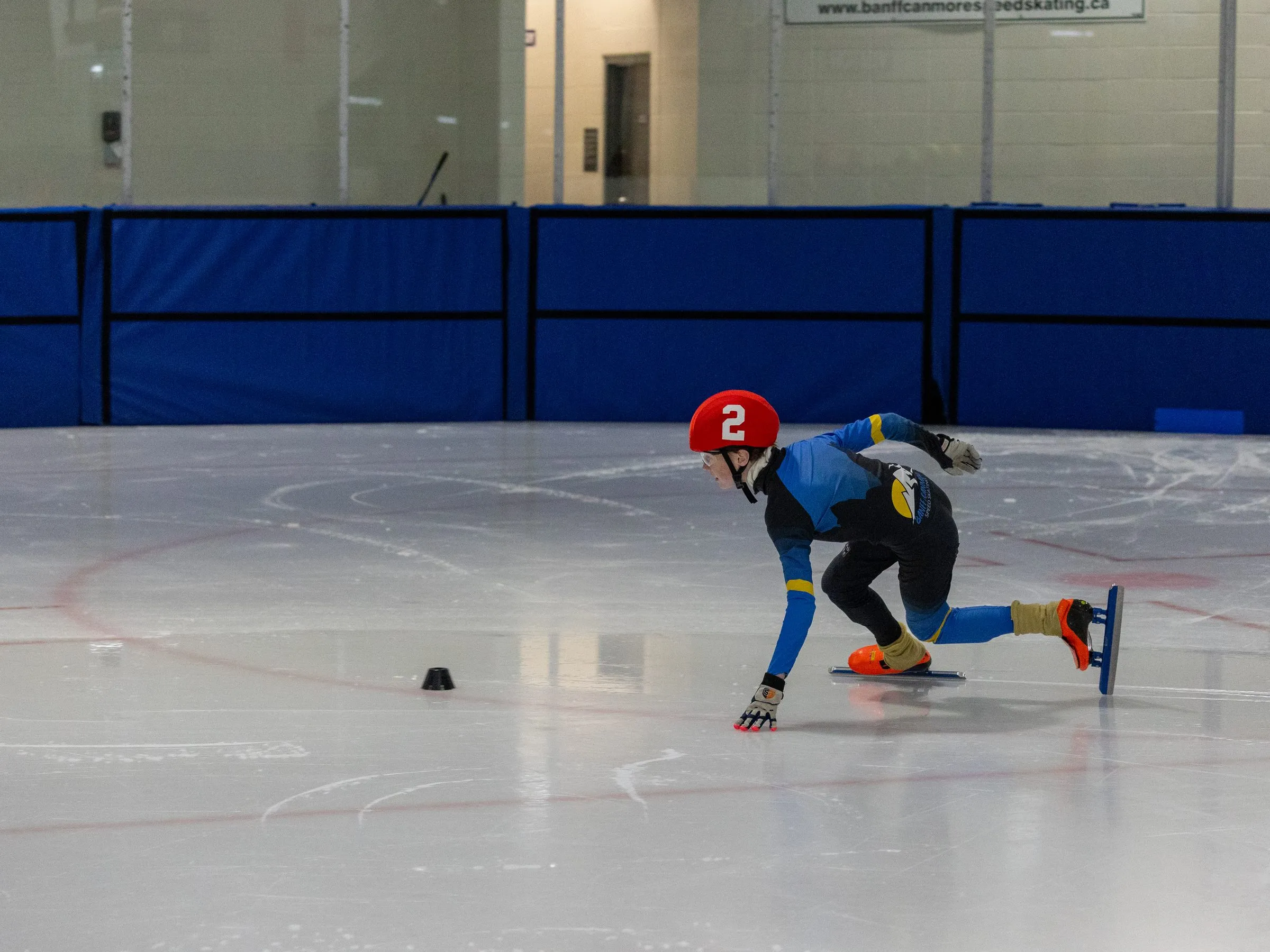 A skater cornering low with a hand on the ice