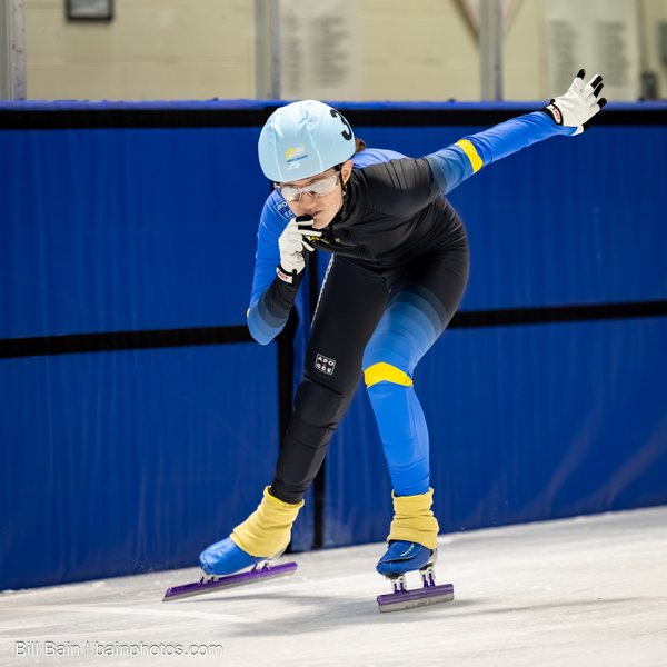 A skater in a light-blue helmet focused through a turn